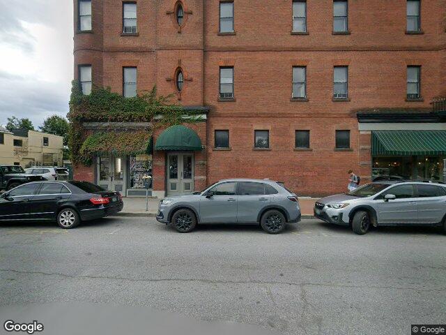 Next Level Barbers storefront on Pearl Street in downtown Burlington, Vermont — red brick building with green awning and ivy